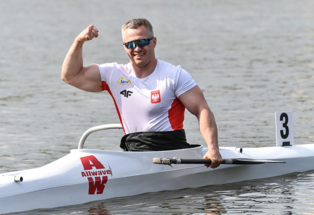 Na zdjęciu znajduje się uśmiechnięty mężczyzna (Jakub Tokarz) w kajaku, na wodzie.