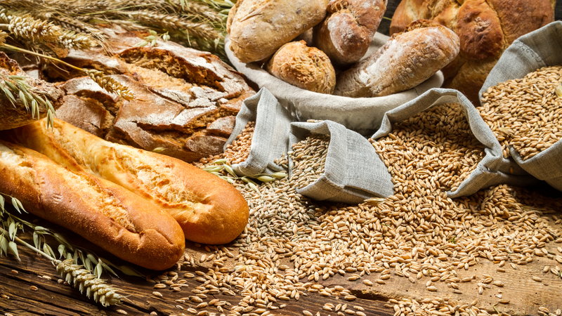 chleb i bułki leżą na ziarnach zboża, które wysypują się z worków