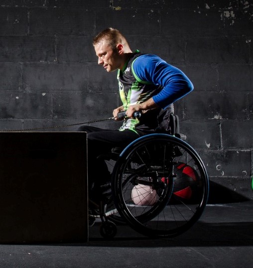 Na zdjęciu mężczyzna na wózku ćwiczący na siłowni.
