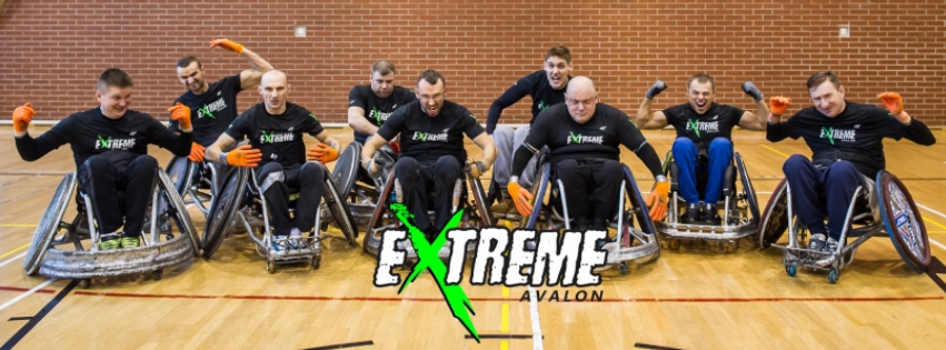 Na zdjęciu drużyna rugby Avalon Extreme. 9 mężczyzn na wózkach do gry w rugby w sali sportowej. 