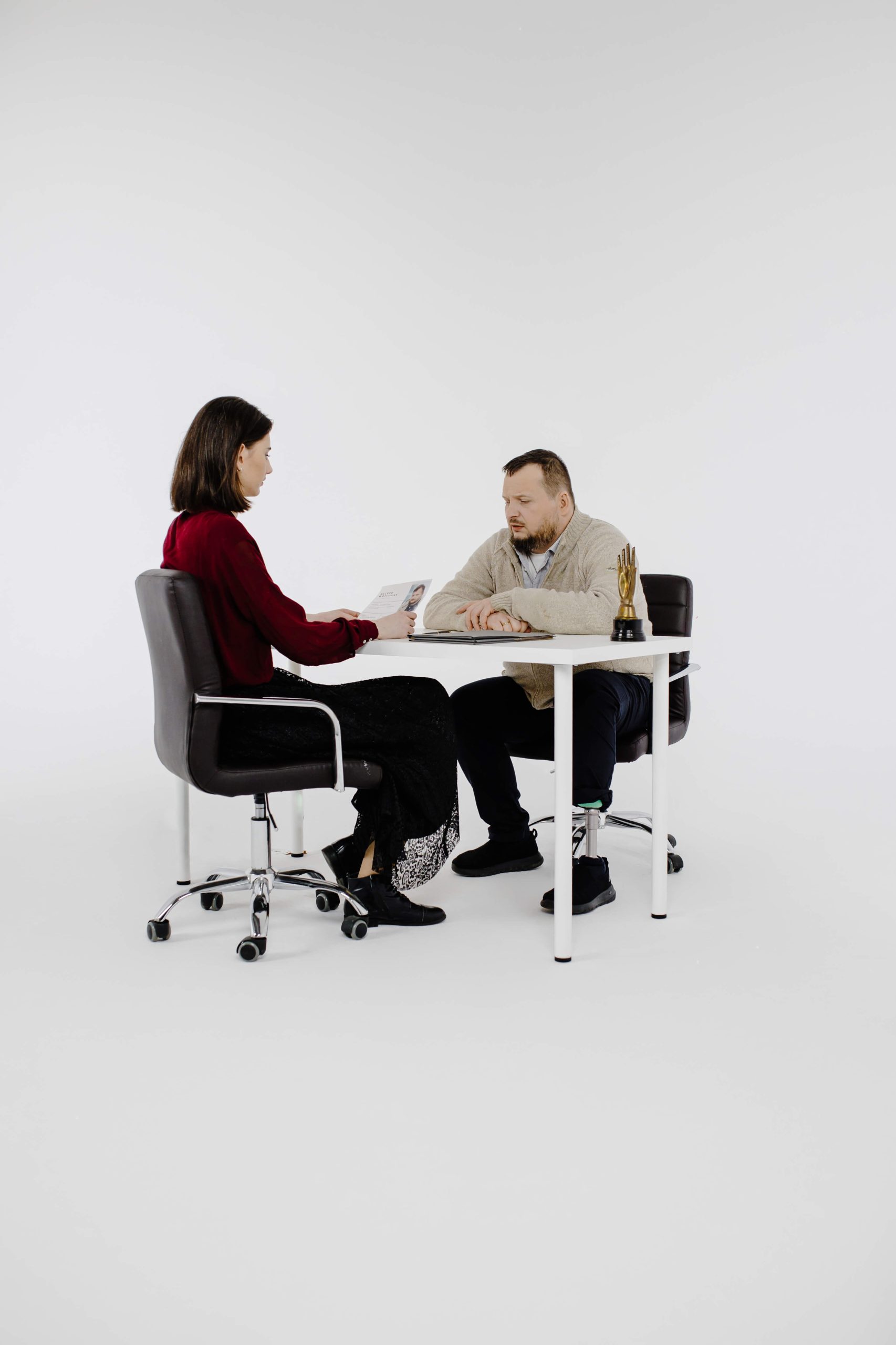 Mężczyzna z protezą nogi siedzi przy biurku i rozmawia z kobietą siedzącą na przeciwko.