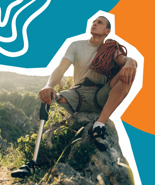 Mężczyzna z protezą nogi siedzi na skałce w górach.