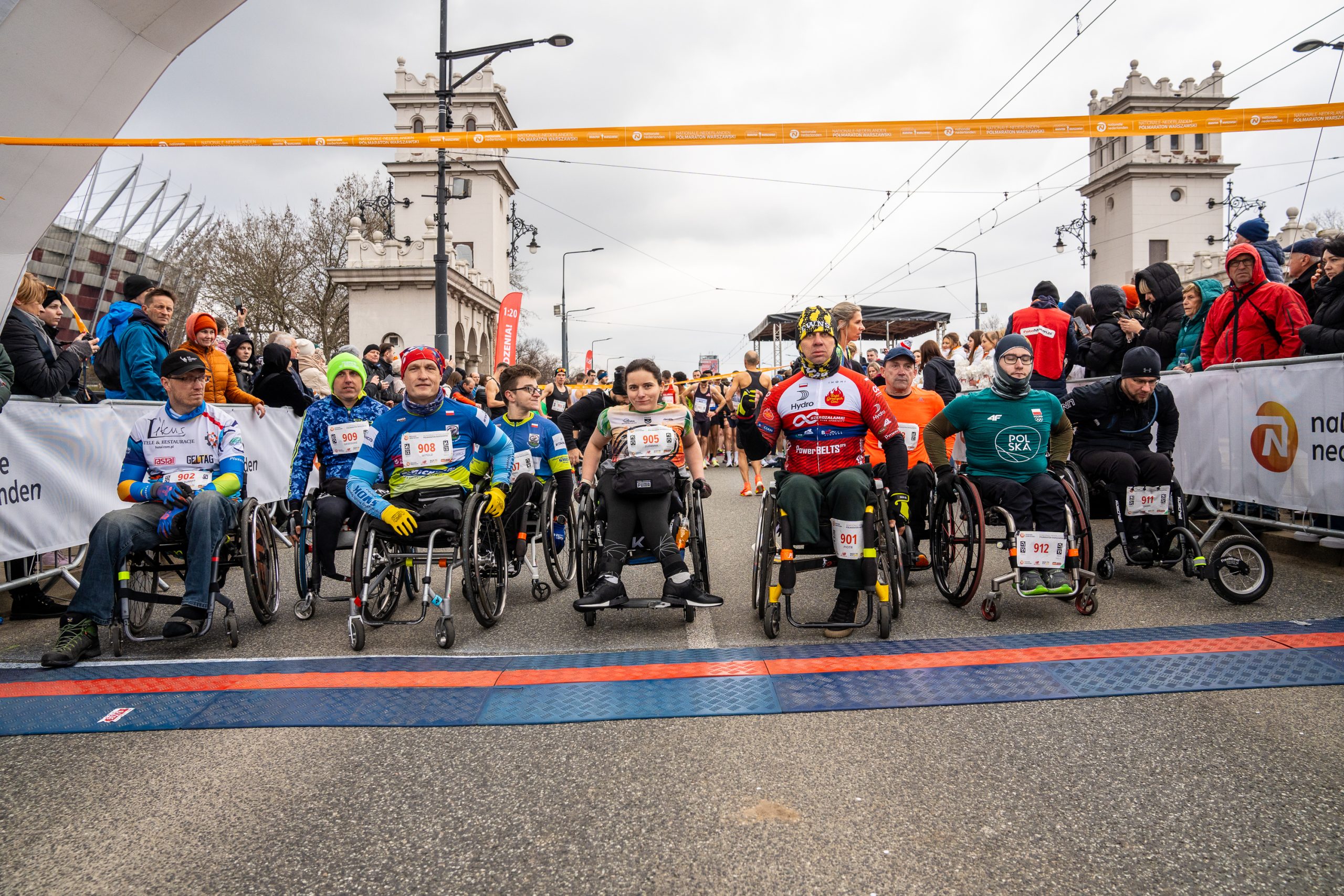 Zawodnicy Maratonu Warszawskiego na wózkach na starcie trasy, przygotowują się do wyścigu.